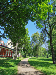 A path next to a beautiful old building in the Summer Garden of Kronstadt against the background of a blue cloudless sky