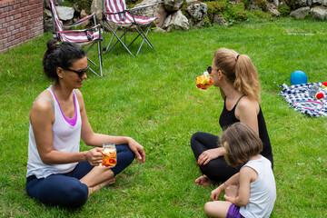 two young women and a little girl in their garden doing yoga and then drinking detox drinks