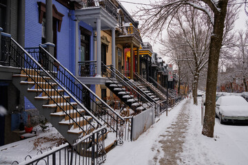 Pedestrian footpath between colorful houses and snow covered park in winter
