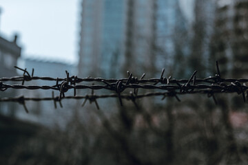 Rusty barbed wire on a blurred dark urban background. Pessimistic scene.