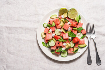Watermelon salad with avocado, cucumber, feta cheese and arugula. Summer fruit salad. Top view, copy space