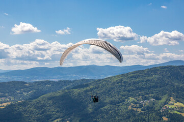 Paraglider pilot hovering over the Żar Mountain on a summer day