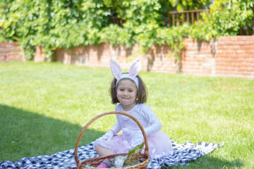 little girl in a bunny costume is having a picnic in the garden of her house.. happy easter.