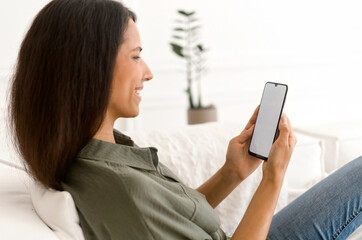 Back view at an empty smartphone screen in hand of an indian woman, mixed-race female holds mobile...