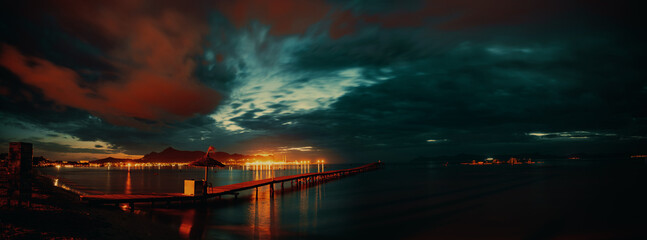 Marine wooden pier on the night shore of the sea bay