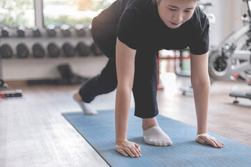 Naklejka na ściany i meble Training gym concept a female teenager doing planking and holding the position for a while as her abdominal and core exercise