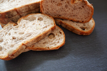 Close-up image of a bread cutting on a black background. Healthy baked bread, whole bread on dark background.