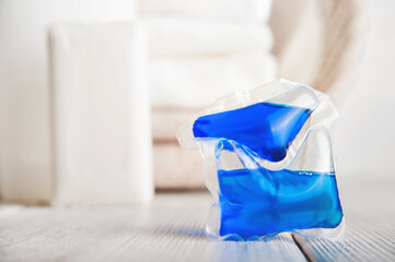 Blue laundry capsule and stack of terry towels. Concentrated detergent and cleanliness...