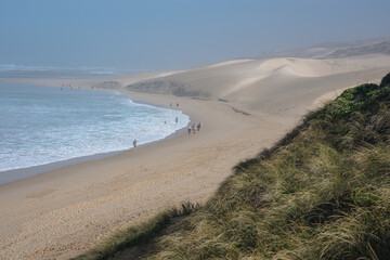 Landscape of beach with people seen walking along the coast