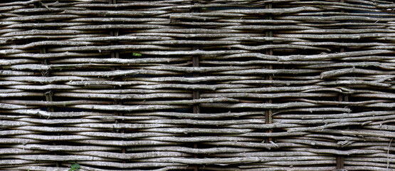 Old brushwood fence. Wicker fence made of willow branches. Beautiful natural background