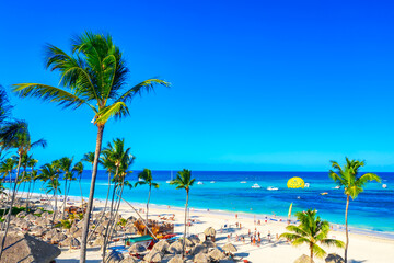 Beautiful atlantic tropical beach with palms, umbrellas and parasailing balloon. Aerial view of Bavaro beach Punta Cana tropical resort in Dominican Republic.