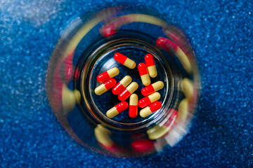 Glass of water and pills on blue background