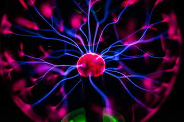 Plasma ball with smooth magenta-blue flames isolated on a black background.