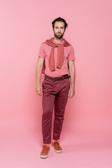 Full length of young man looking at camera on pink background