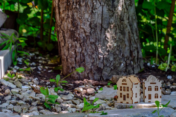 toy houses on a stone slab against the background of a tree trunk