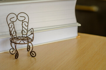toy iron chair on a wooden table, with a background of books