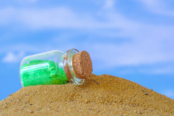 small glass jar with a cork lying on the sand