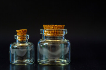 small glass jars with a cork on a black background