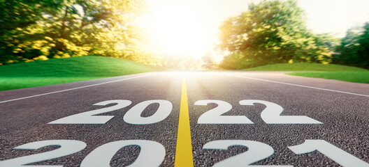 Road into evening sunset with the numbers 2021 2022 ahead on asphalt