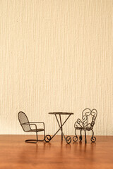 toy iron chairs and table on a beige wall background