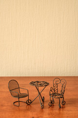 toy iron chairs and table on a beige wall background