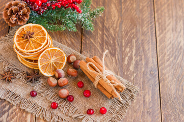 Christmas composition with spruce tree branches, cinnamon sticks, dried slices of oranges, nuts and anise on wooden background. Rustic style.