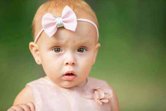 The face of a beautiful little girl on a green background. One year old child.