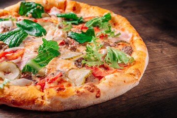 Pizza with cheese, Bolognese sauce, minced meat, bacon, tomato and vegetables. Italian pizza on wooden background.