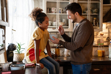 Happy father with his black daughter spending time together and having fun at home