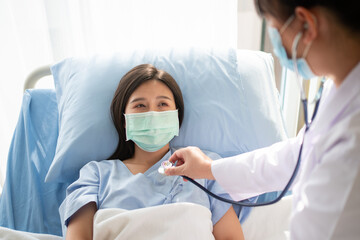 Women Asian doctors hold the patient hand and encourage and provide medical advice While doctors use Stethoscope for checking the patient heart in bed. Concept of Care and compassion