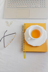 Home office desk workspace with laptop, glasses, paper clips and stationery on white background. Flat lay, top view. Women's, girl boss work or business concept.
