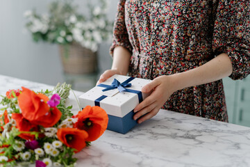 Woman in dress putting gift on marble table - Powered by Adobe