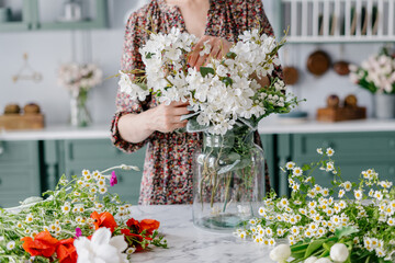 Woman arranging bouquet, putting it in glass jar