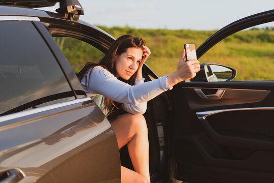 Young woman are traveling on the roads by car, stopped at the side of the road and take pictures with a smartphone Vacation concept