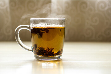 A glass cup of black hot tea on a light table