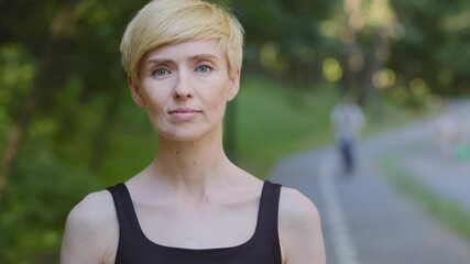 Outdoors portrait close-up middle aged friendly female face mature woman trainer runner jogger athletic 40s blonde lady standing in park looking at camera with calm expression human headshot outdoor