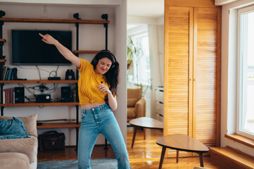 Woman dancing while listening a music on a headphones at home