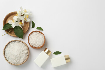 Flat lay composition with beautiful jasmine flowers, sea salt and skin care products on white...