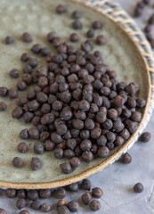 Plate of black chickpea on grey table closeup