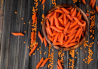 Uncooked red lentils pasta in a bowl on dark wooden background