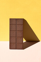 Dark chocolate bar with heavy shadows on colorful background
