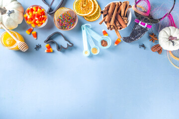 Halloween Gingerbread Cookies cooking background. Autumn holiday baking concept, ingredients, spices, halloween symbol cookie cutters - pumpkin, ghost, bat, witch hat, top view blue table copy space