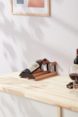 Interior photo: stylish wine rack with bottle is located on the table near wine glasses. Wine shelf...