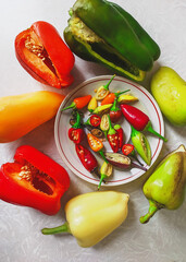 different fruits of peppers with seeds in a plate and on the table.