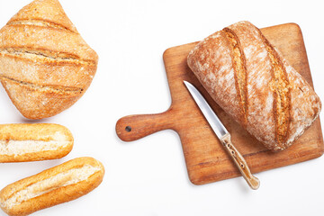 freshly baked bread on wooden cutting board isolated on white background, top view