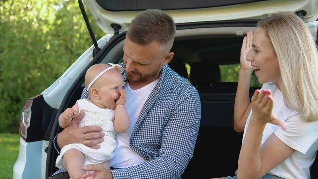 Family Leisure Outside The City. White Family Car. Happy Father, Mother And Baby. Caring For Babies. Father Holds Baby Daughter In His Hands