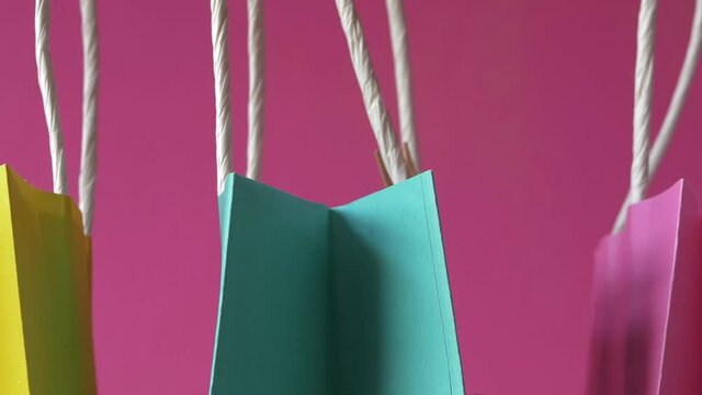 Row of colorful gift bags on pink background close up