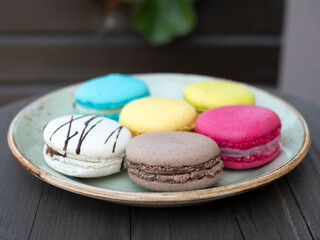 Six colored macarons on the plate. Meringue-y sandwich cookies. Perfect little indulgence. Colorful confections