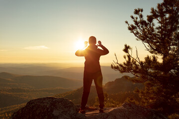 a girl meditates on the top of a mountain at sunrise, sunset. mountain trekking, climbing, yoga in autumn or spring. active recreation. the energy and rays of the sun for human nutrition. HIRES