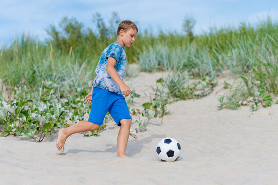 Young boy play soccer ball on the beach. Summer sport concept. Horizontal sport poster, greeting cards, headers, website